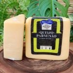 Queijo parmesão Sérvulo fracionado, em embalagem à vácuo sobre mesa de madeira.