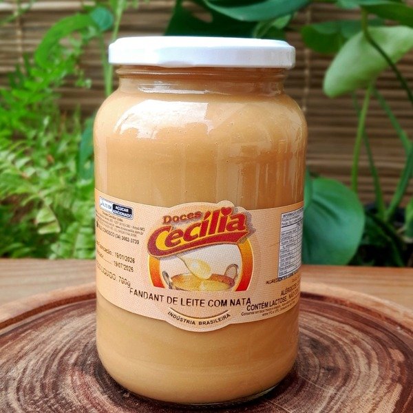 doce-de-leite-com-nata Doce de leite com nata da Doces Cecília, em pote de vidro com 700 gramas, sobre mesa de madeira.