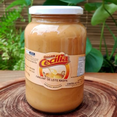 Doce de leite com raspas da Doces Cecília, em pote de vidro com 700 gramas, sobre mesa de madeira.