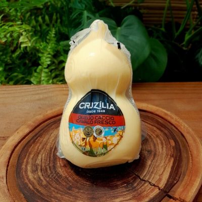 Queijo Caccio Cavalo Cruzília, embalado sobre mesa de madeira.
