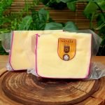 Queijo Gouda Val di Fiemme fracionado e embalado, sobre mesa de madeira.