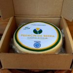 Queijo Canastra Pedacin da Serra em peça inteira embalada à vácuo, sobre mesa de madeira.