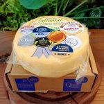 Queijo Reinaldo Canastra em peça inteira embalada à vácuo, sobre mesa de madeira.