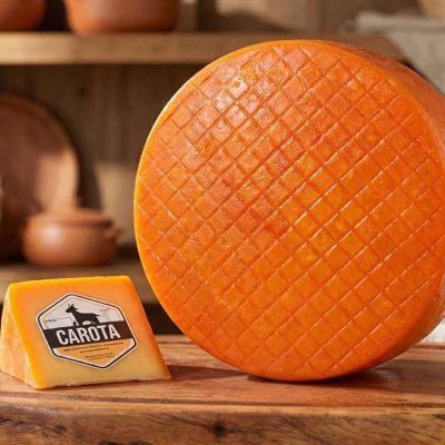 Queijo Carota artesanal Minas Cabra sobre mesa de madeira.