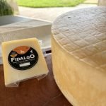 Queijo Fidalgo Minas Cabra sobre mesa de madeira.